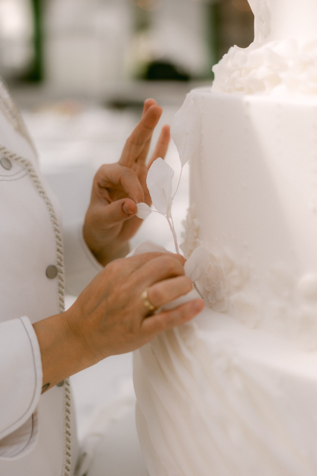 Close-up of a hand-crafted sugar spire, pearl piping and sugar flowers on a wedding cake