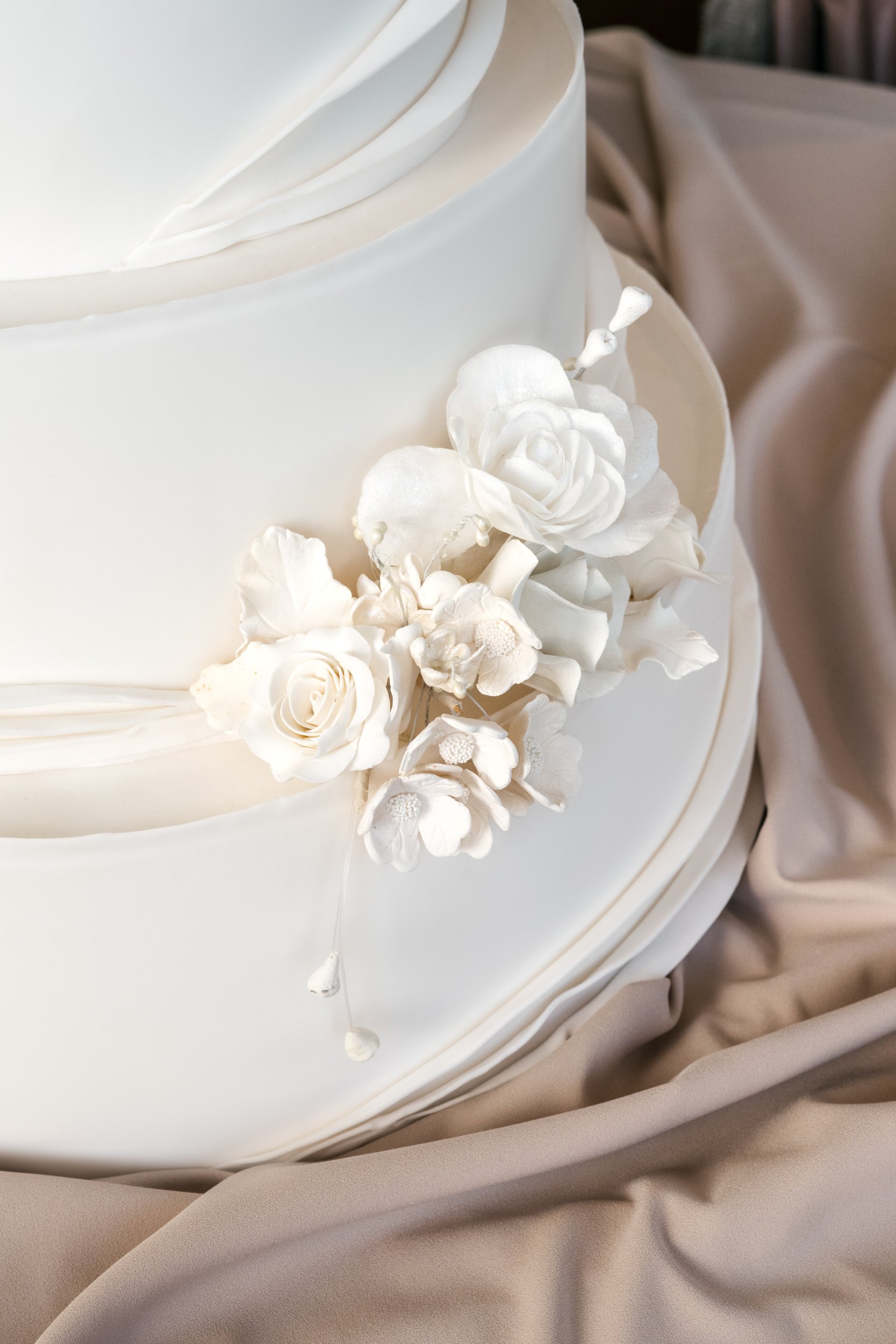 Soft nude satin folds with ivory and blush sugar roses on a white cake