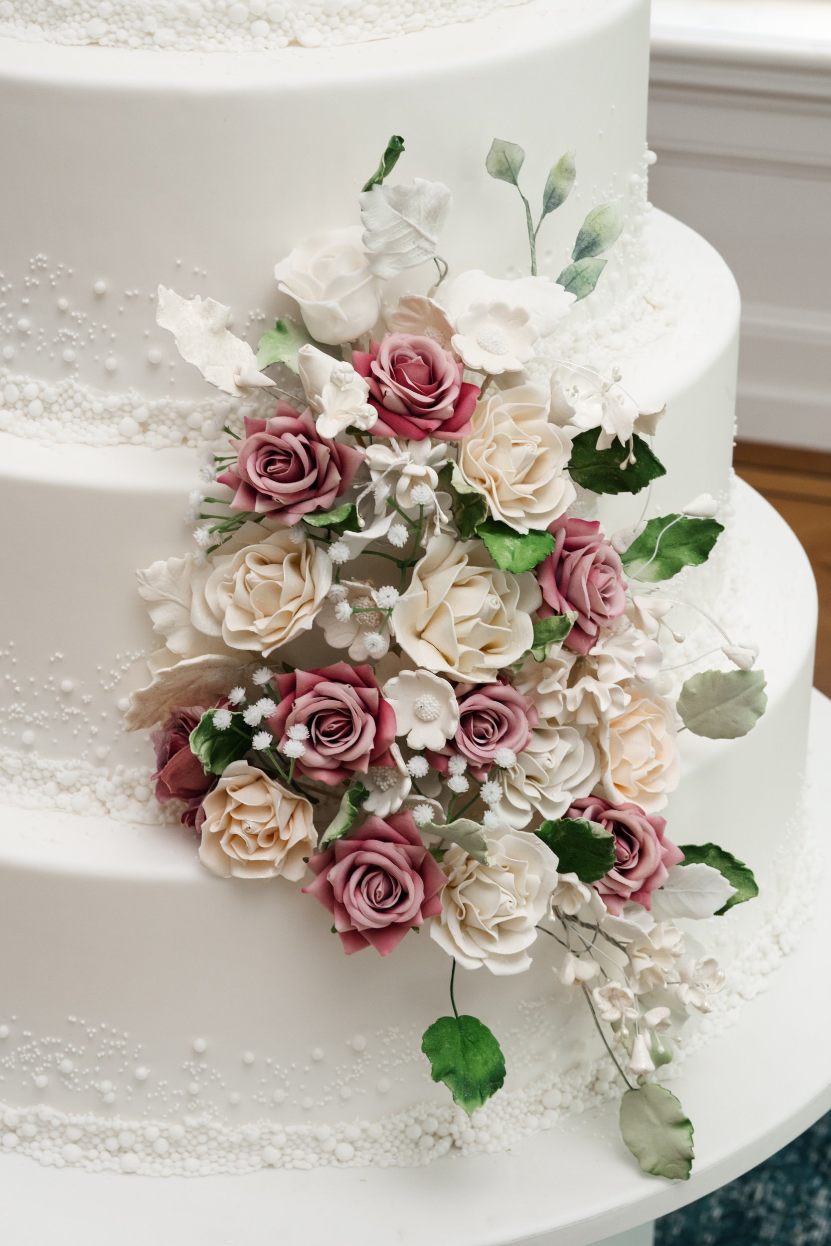 Hand-made ivory and blush sugar roses cascading over a white cake