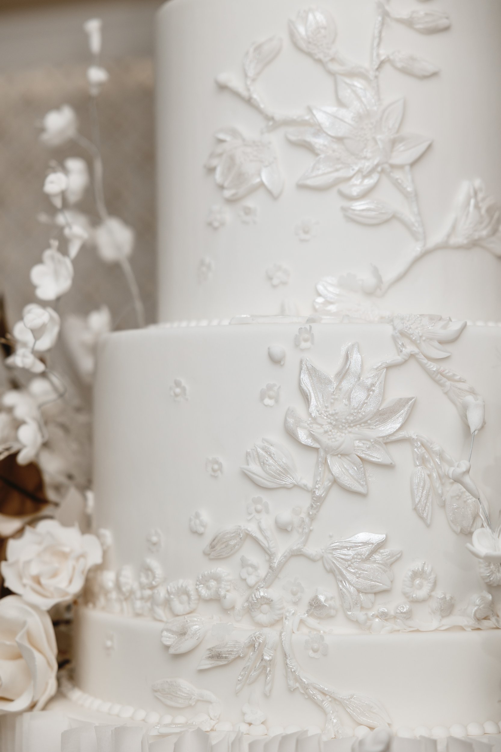 Hand-piped relief flowers and leaves on a white fondant surface